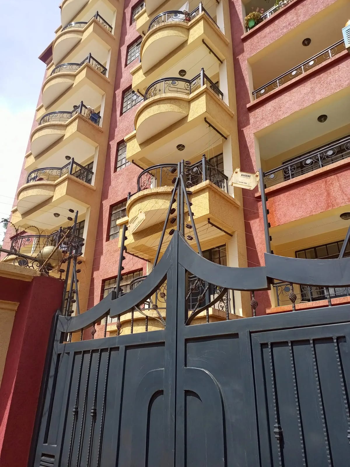Multi-story residential building with curved balconies and ornate gate