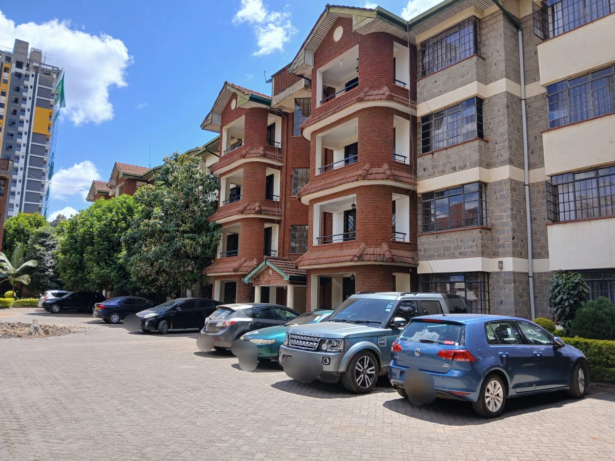 Red brick residential building with shared parking compound