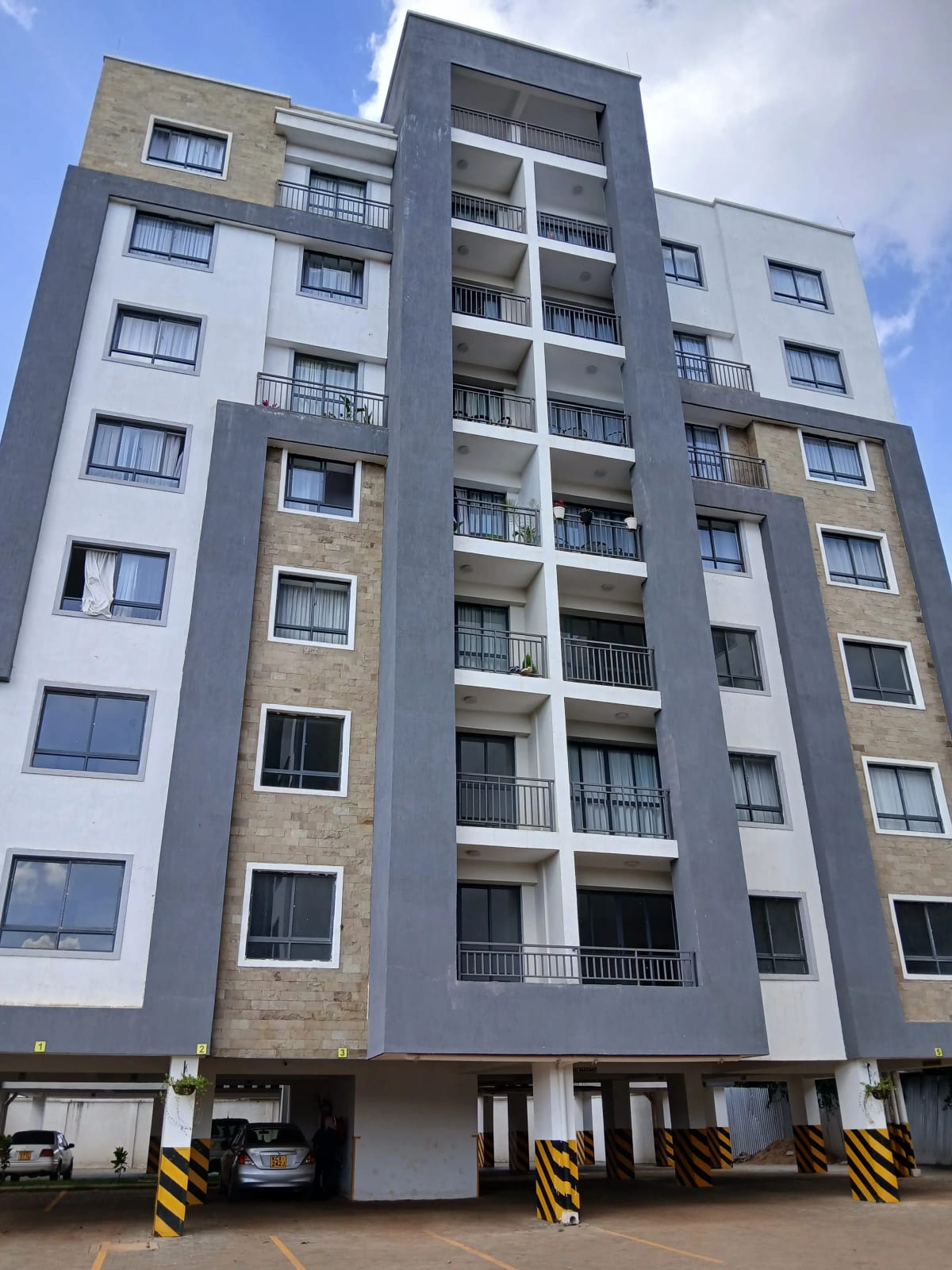 Modern multi-story residential building with balconies and parking