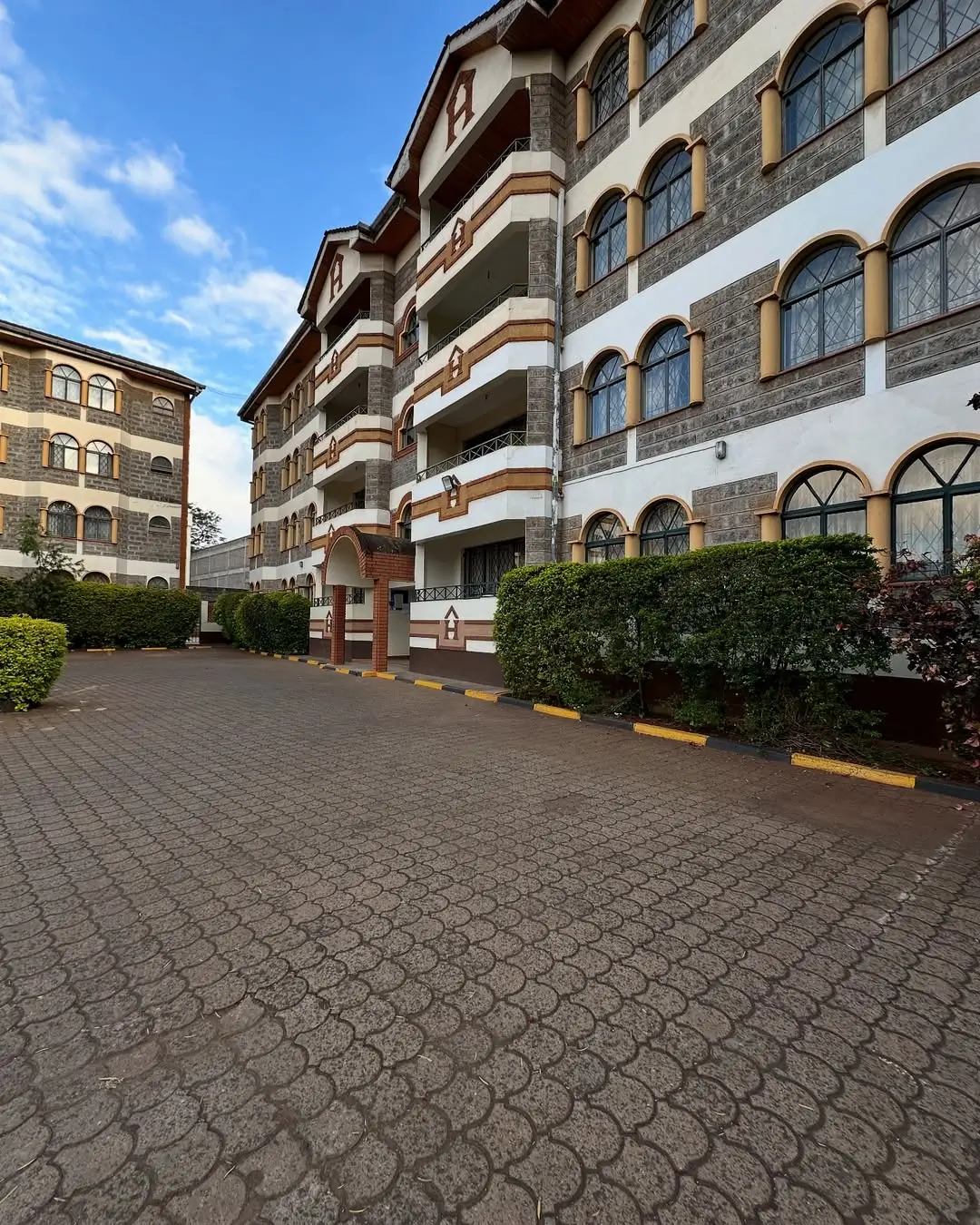 Multi-story residential building facade with manicured compound grounds