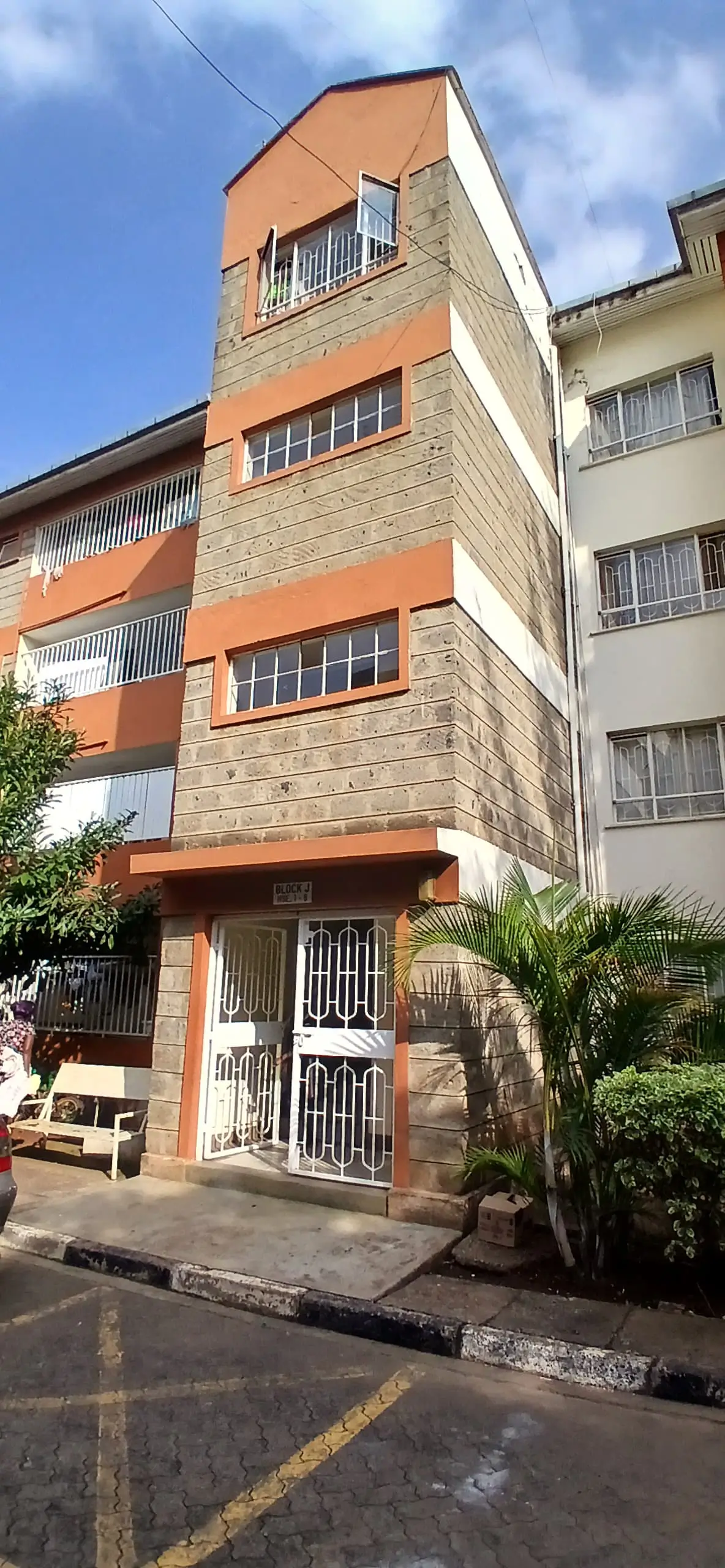 Modern multi-story residential building with orange and stone facade