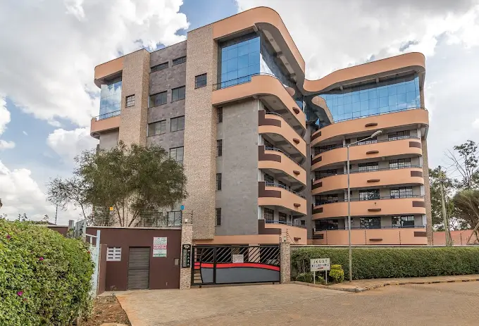 Modern multi-story residential building with curved balconies and parking