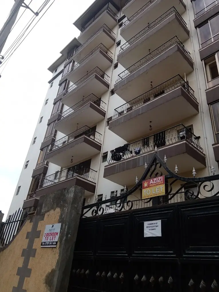 Multi-story residential building facade with balconies and black gate