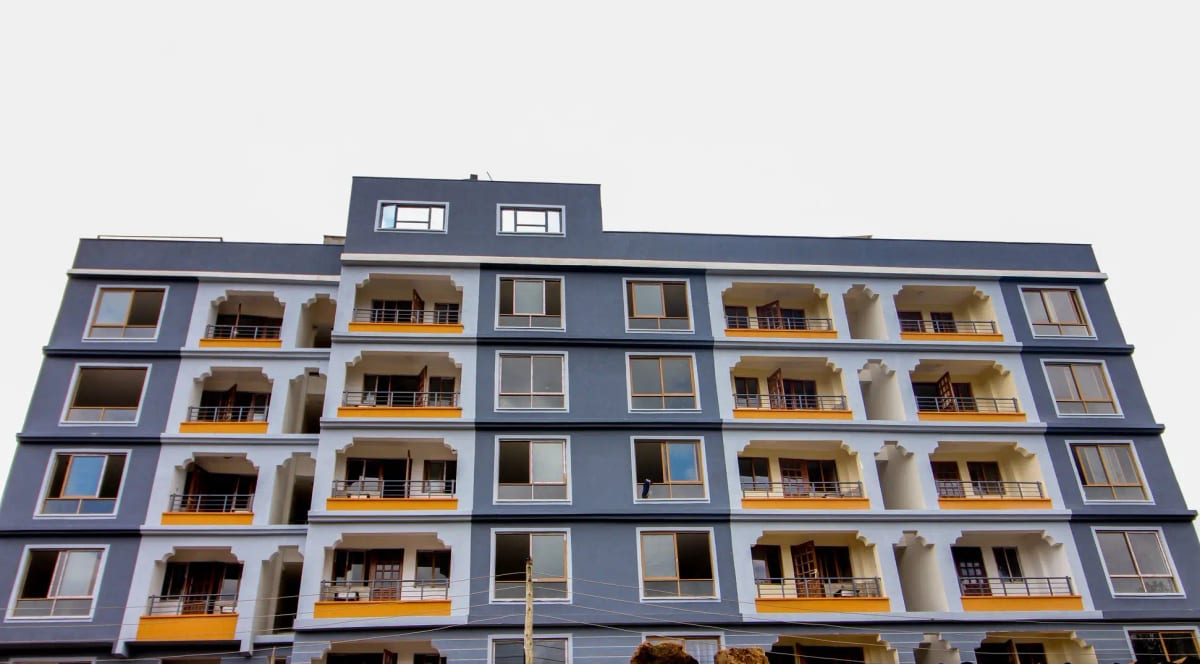 Modern multi-story residential building with blue facade and balconies