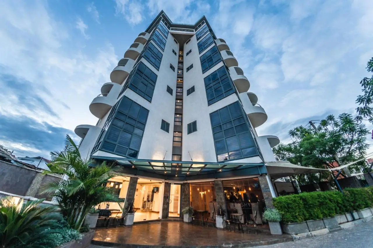 Modern residential tower with curved balconies and lit ground floor