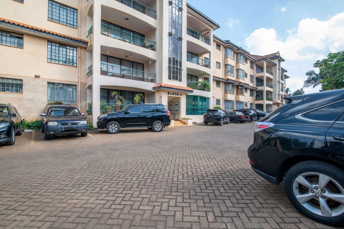 Spacious paved parking lot with multiple vehicles and residential building
