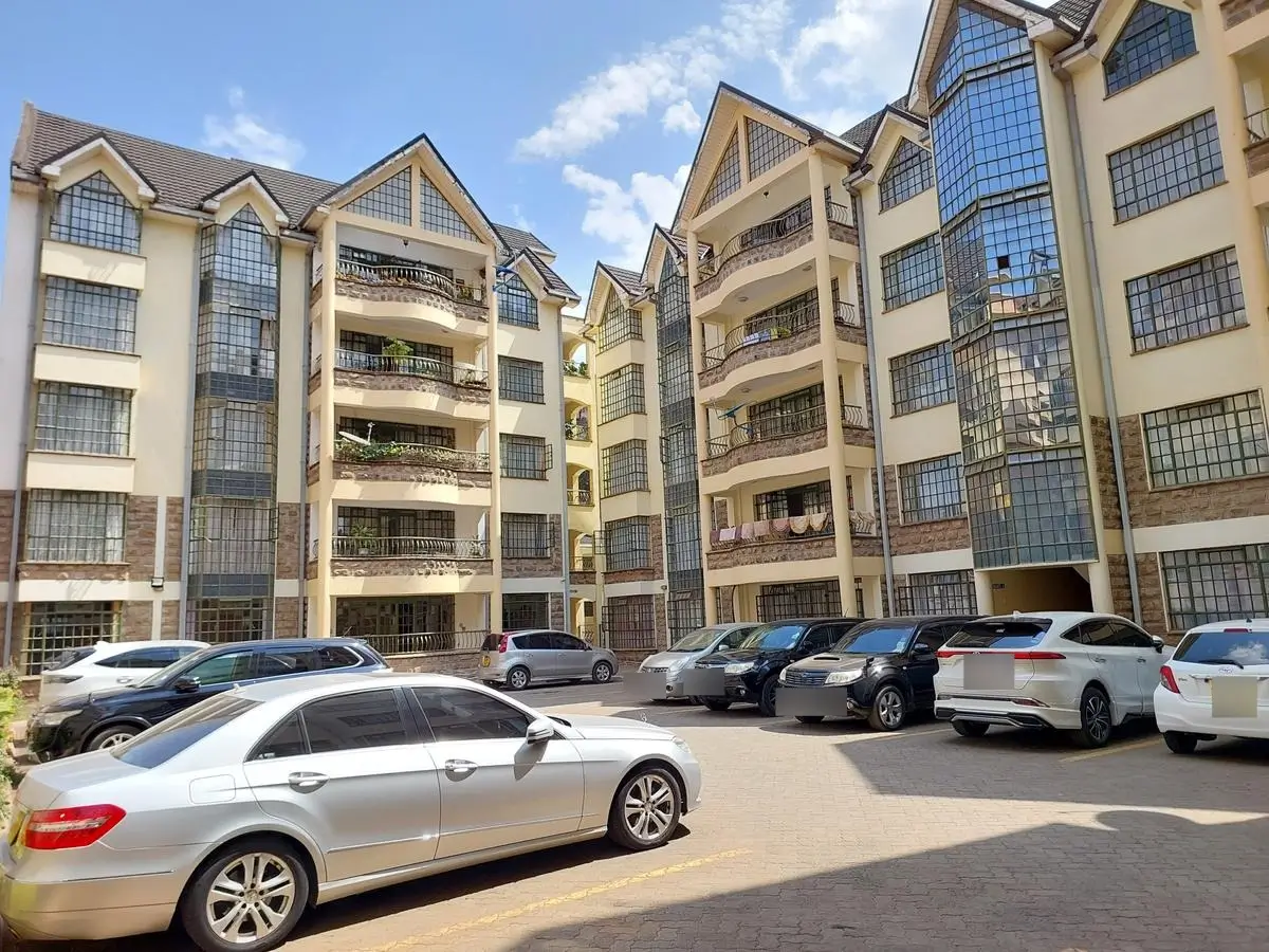 Multi-story residential compound with parking lot and vehicles