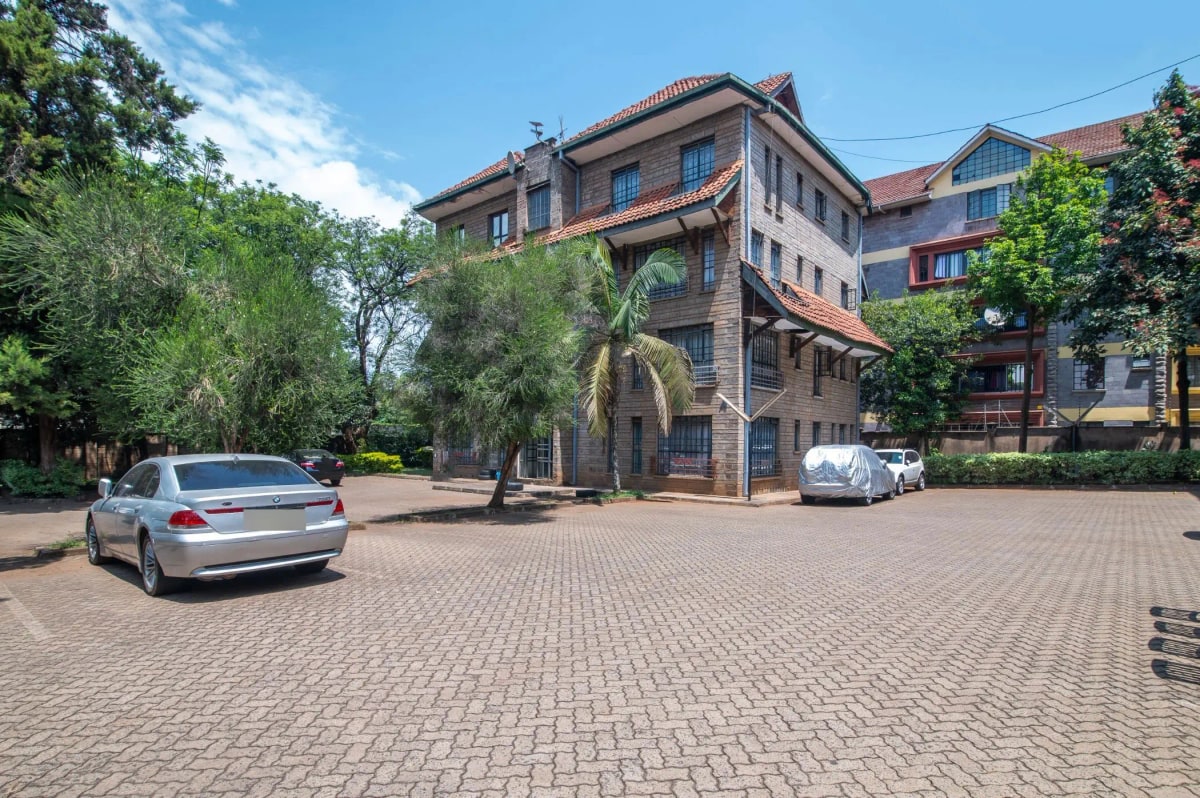 Multi-story residential building with paved compound and parking area