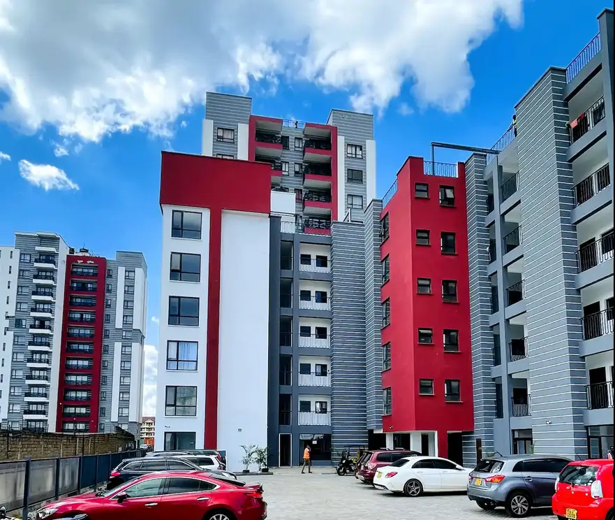 Modern apartment complex with red and white facade, ground-level parking