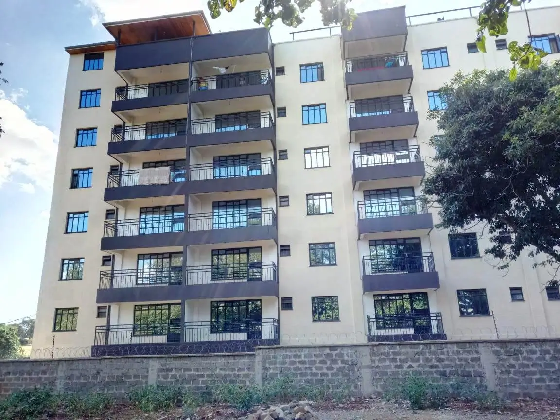 Multi-story residential building facade with balconies and stone boundary wall