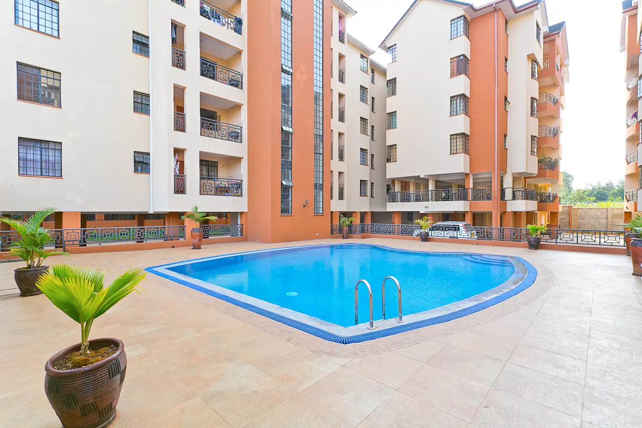 Bright blue swimming pool with lounging deck and compound buildings