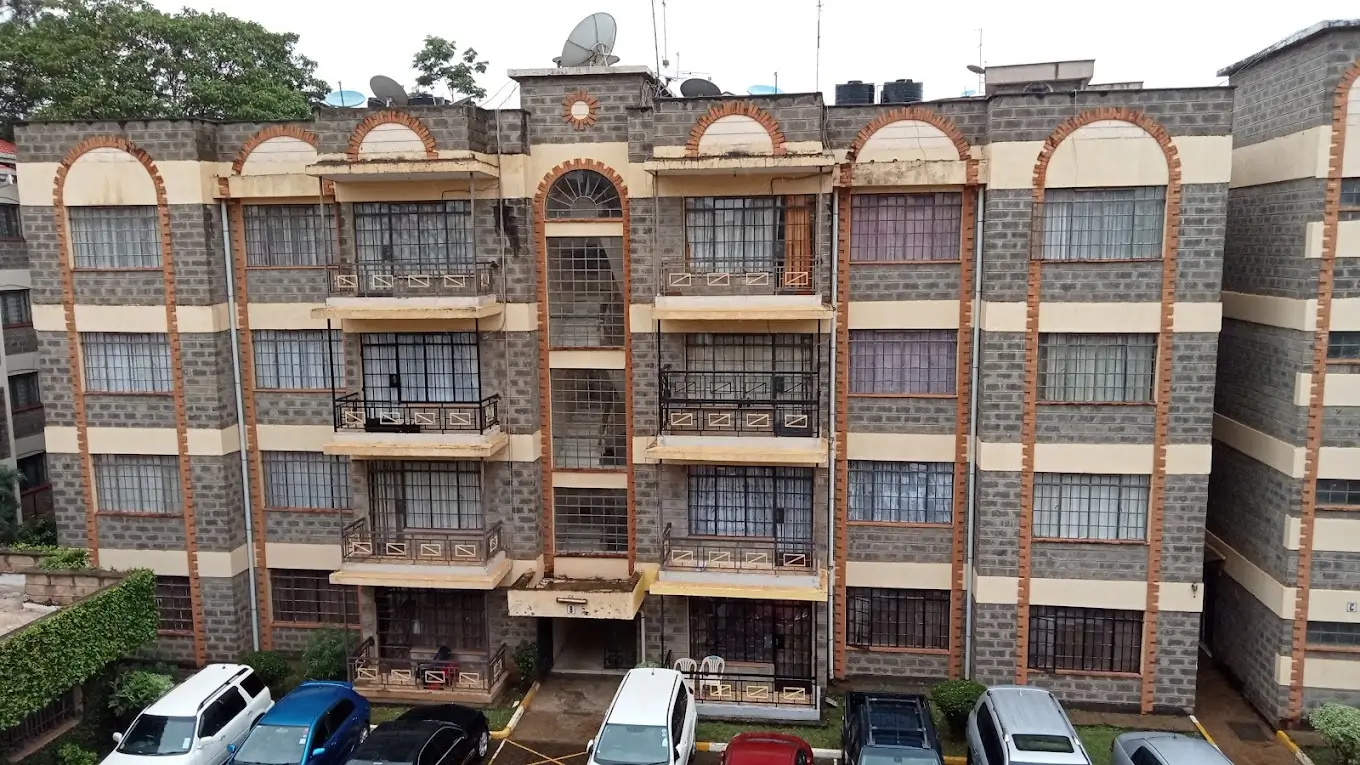 Multi-story residential building facade with parked cars below