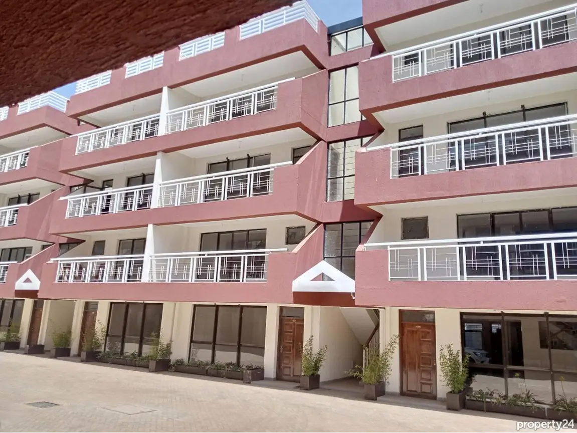Modern pink apartment building facade with balconies and ground level