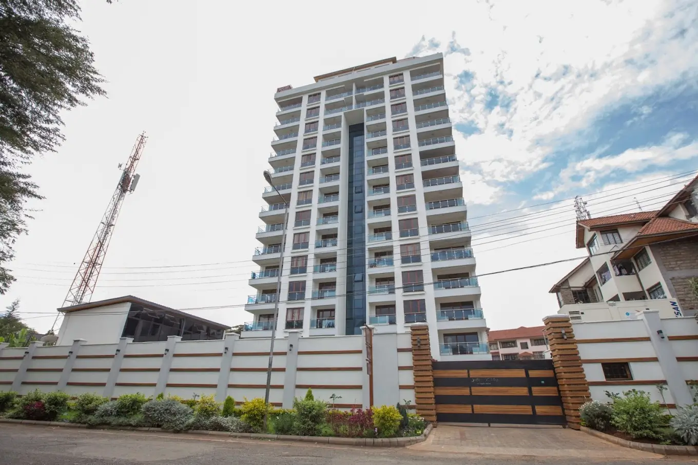 Modern multi-story residential building with white boundary wall