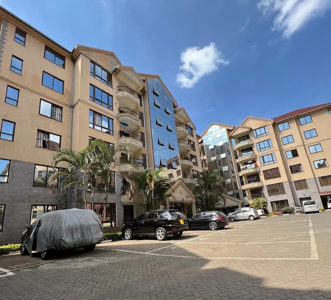 Multi-story residential compound with parking area and landscaping