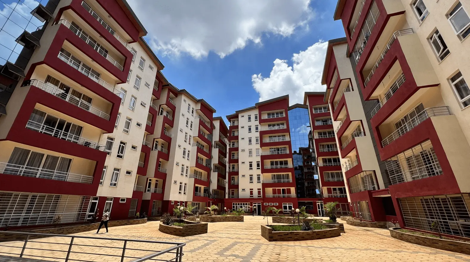 Multi-story residential complex with red and cream facades, central courtyard