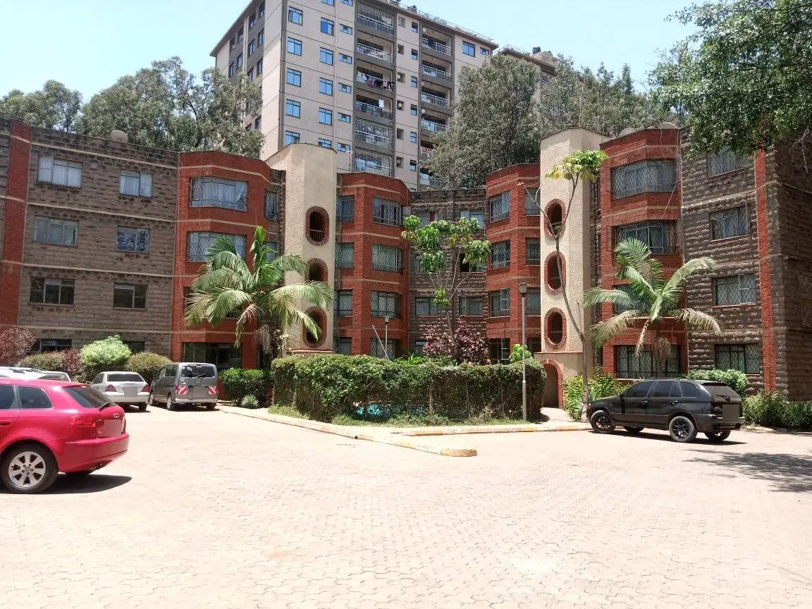 Red brick apartment complex courtyard with mature landscaping and parking