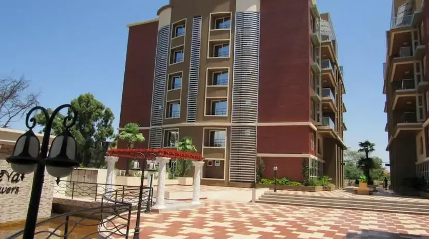 Multi-story residential building with red brick facade and landscaped compound