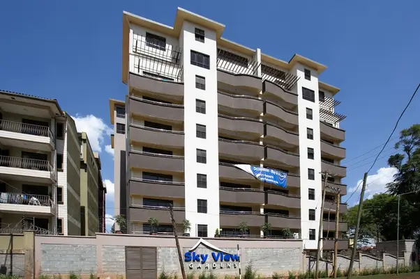 Modern multi-story residential building with balconies, clear blue sky
