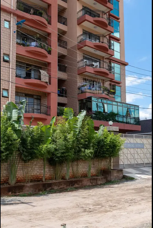 Red-brick apartment building facade with balconies and landscaping