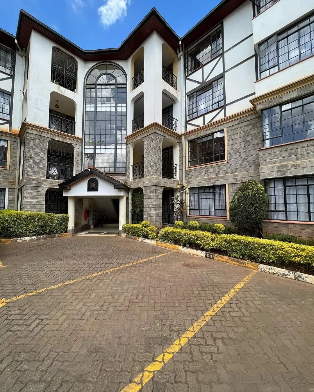 Multi-story residential building facade with manicured compound entrance