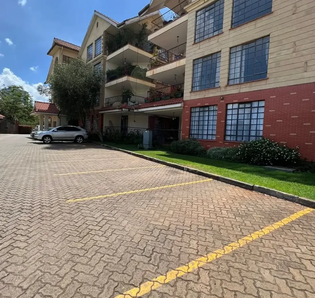 Multi-story residential building with paved driveway and parking bay