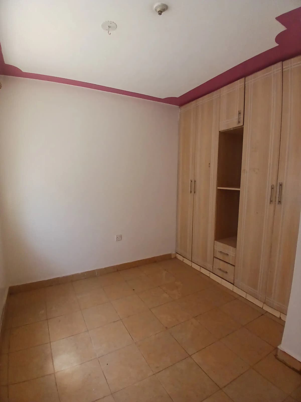 Spacious bedroom with wooden wardrobe and terracotta tile flooring