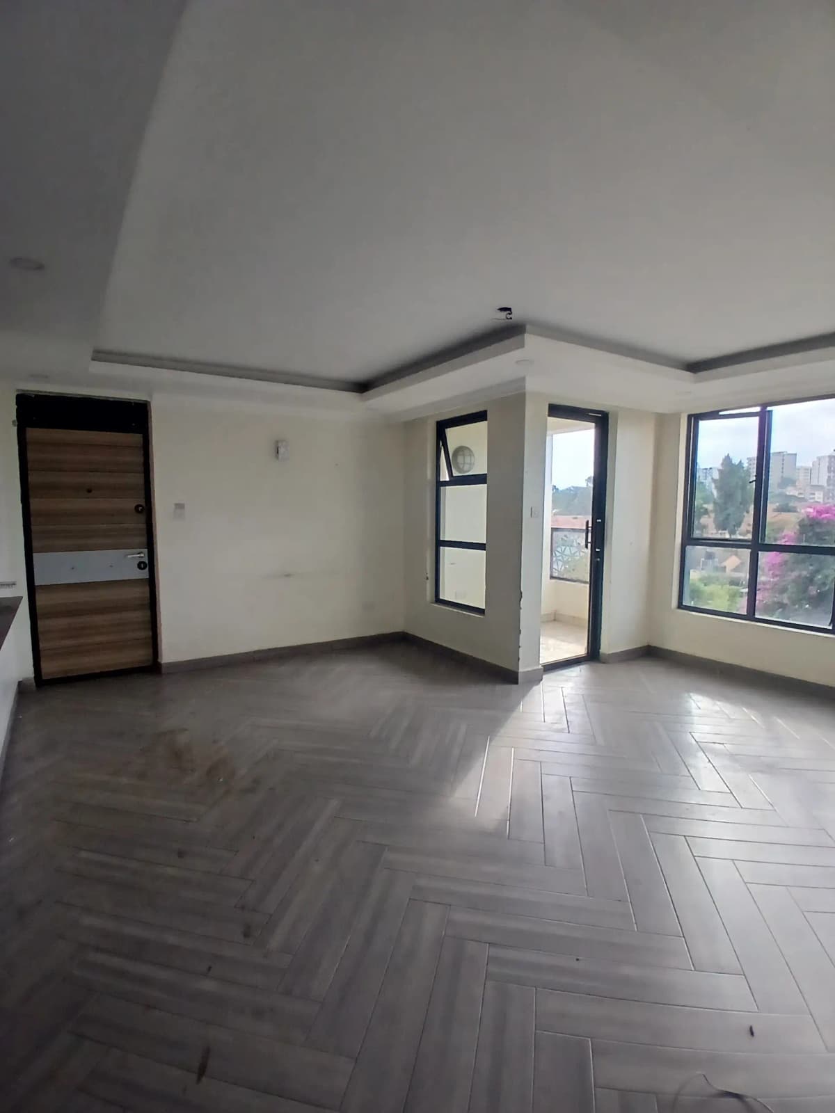 Spacious living room with herringbone flooring and balcony access