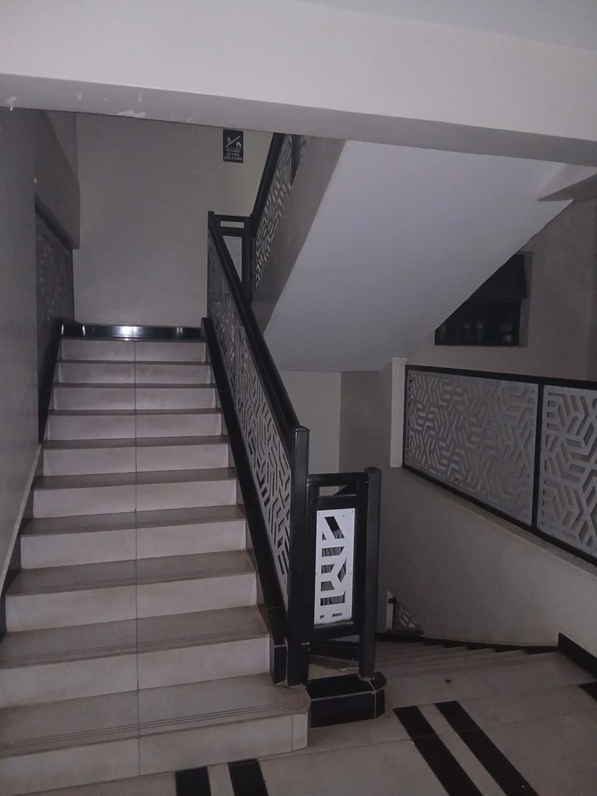 Interior staircase with black metal railing and tile flooring