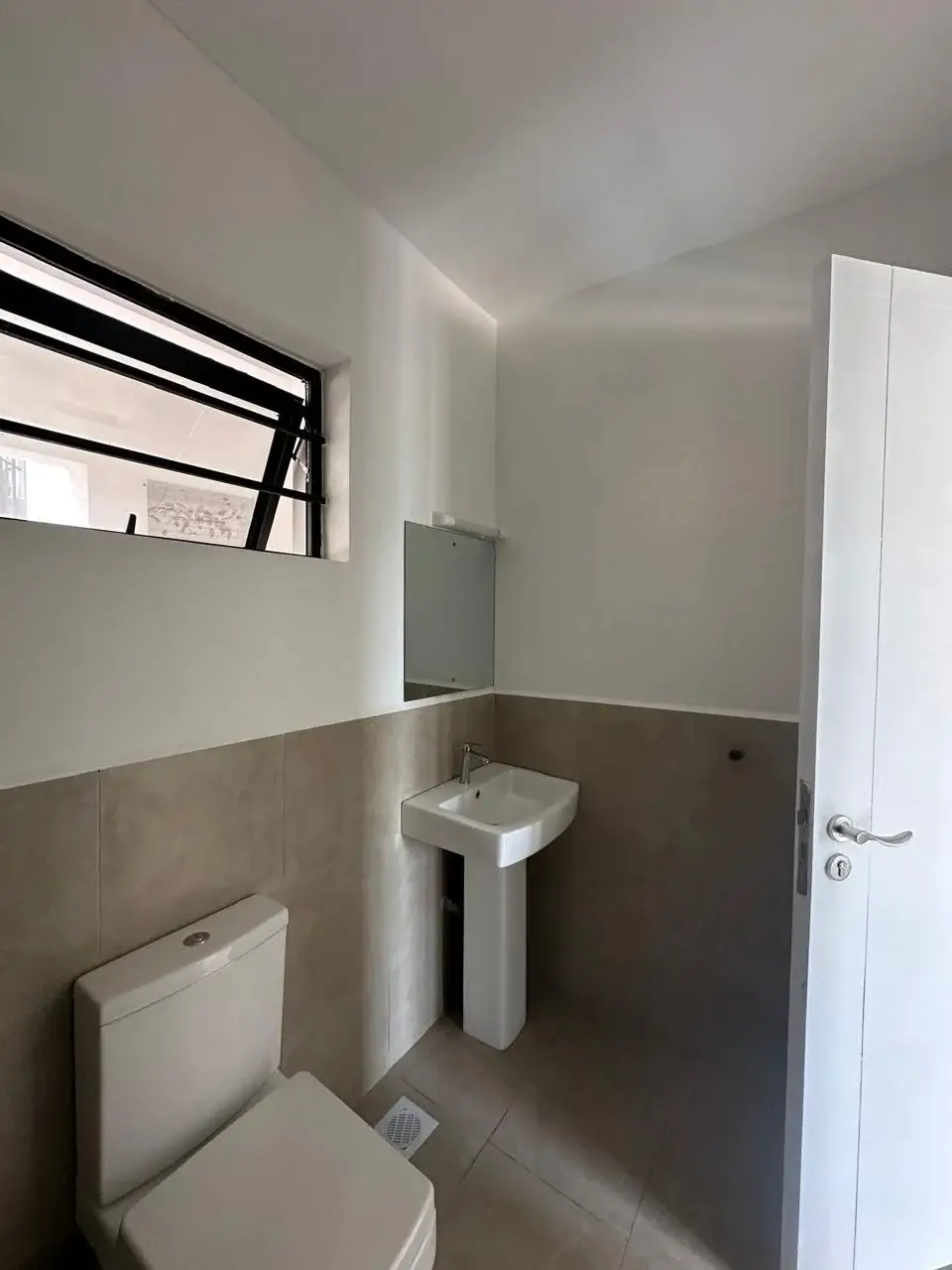 Compact bathroom with toilet, pedestal sink, and window