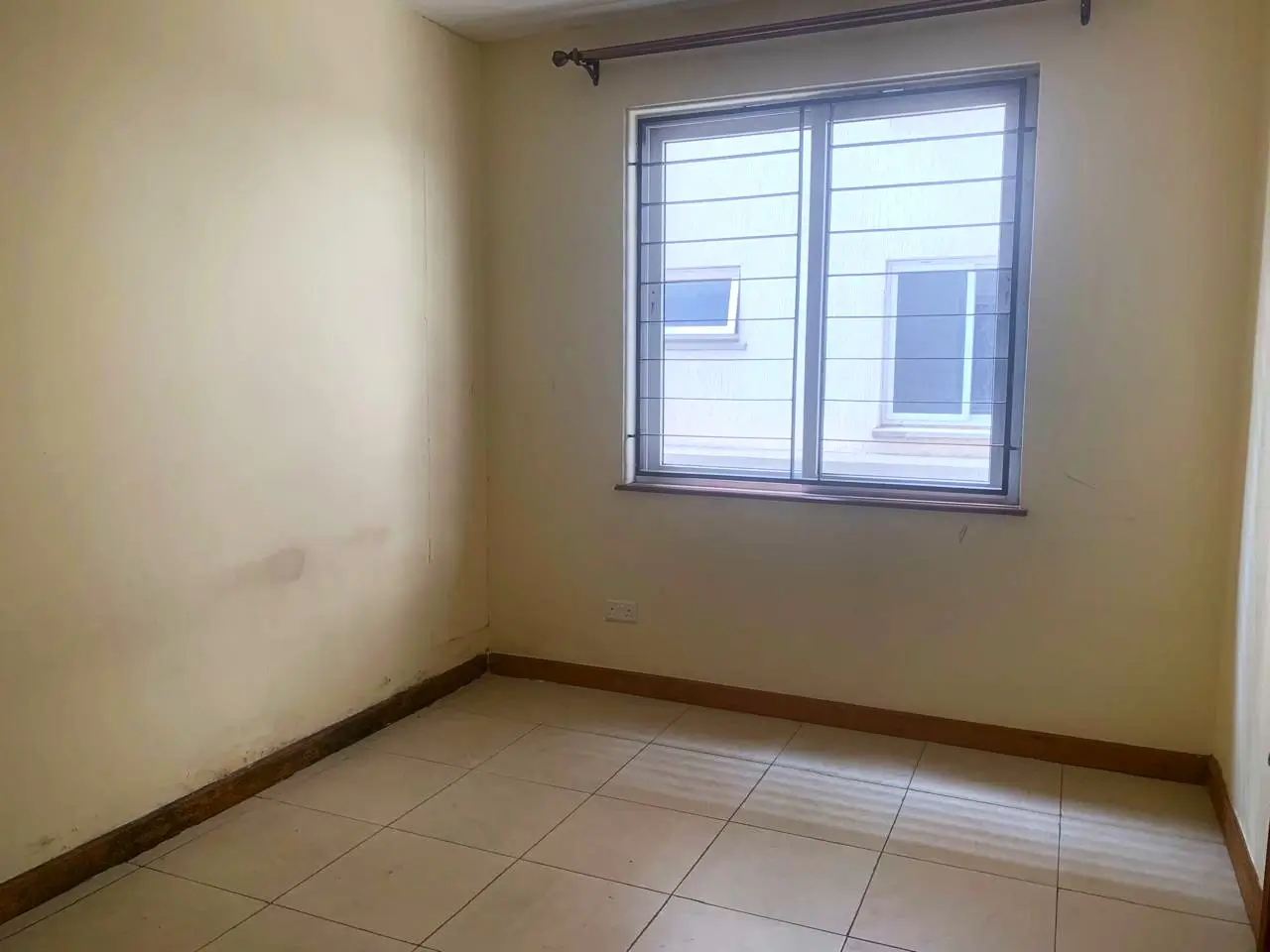 Empty bedroom with tiled floor and natural light