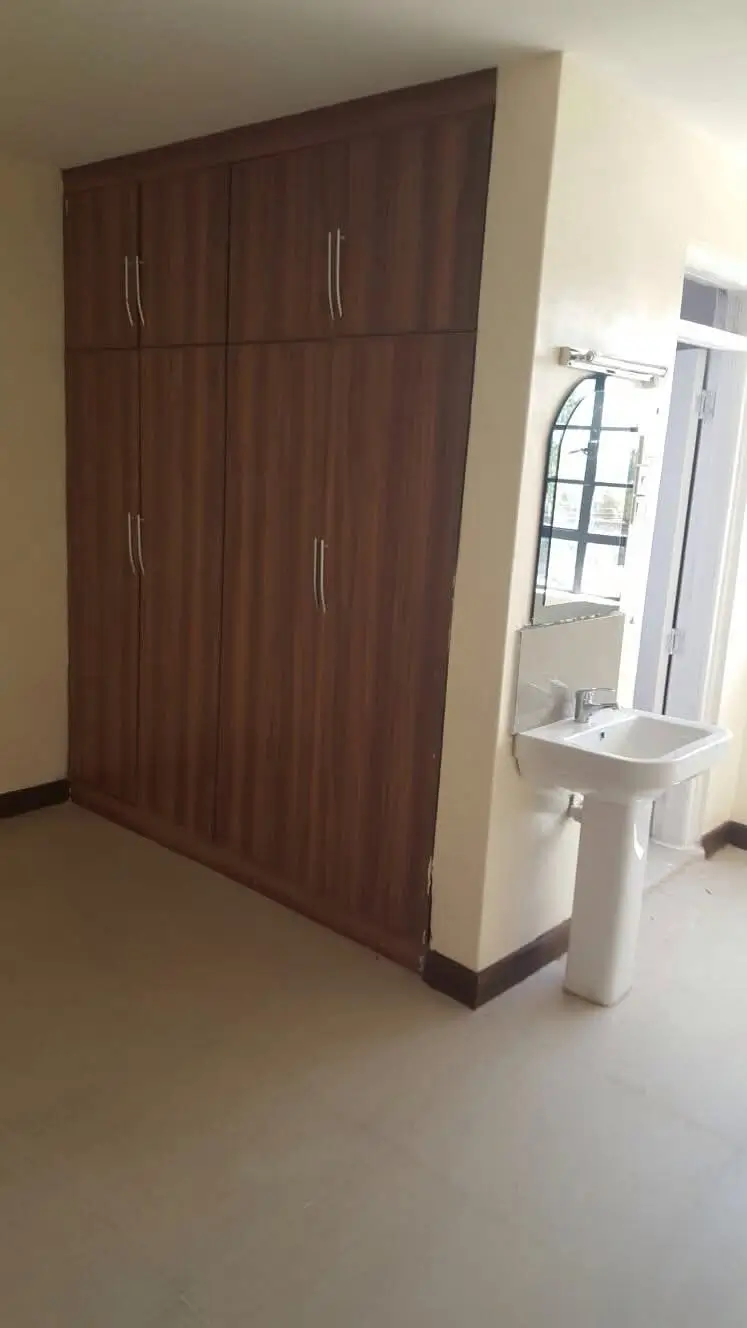Spacious bedroom with large dark wood built-in wardrobe