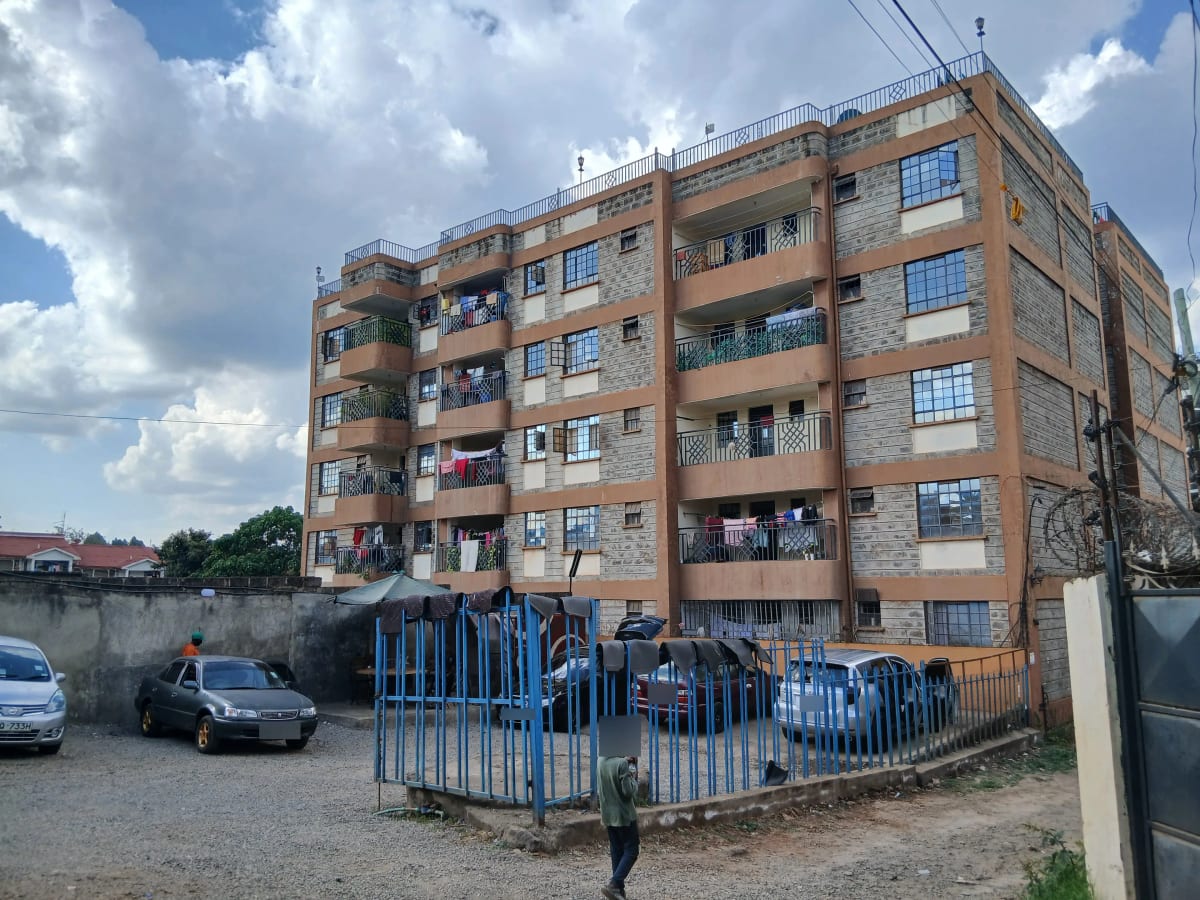 Multi-story residential building facade with parking compound