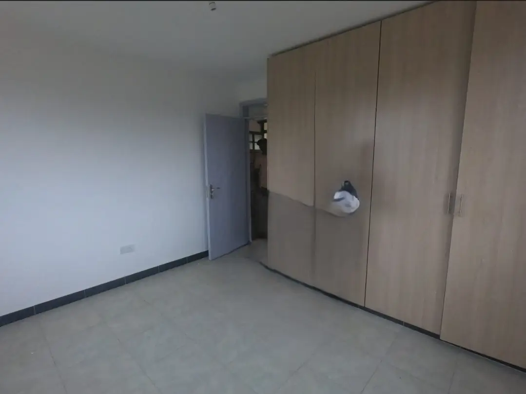 Empty bedroom with built-in wardrobe and door entrance