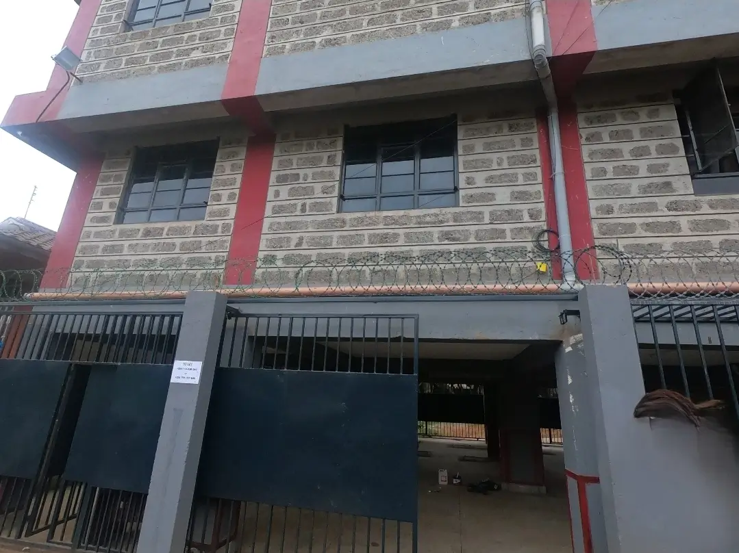 Multi-story residential building facade with red trim and metal gates