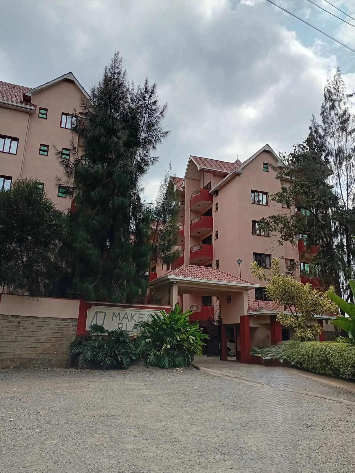 Multi-story residential building with red accent entrance and landscaped compound