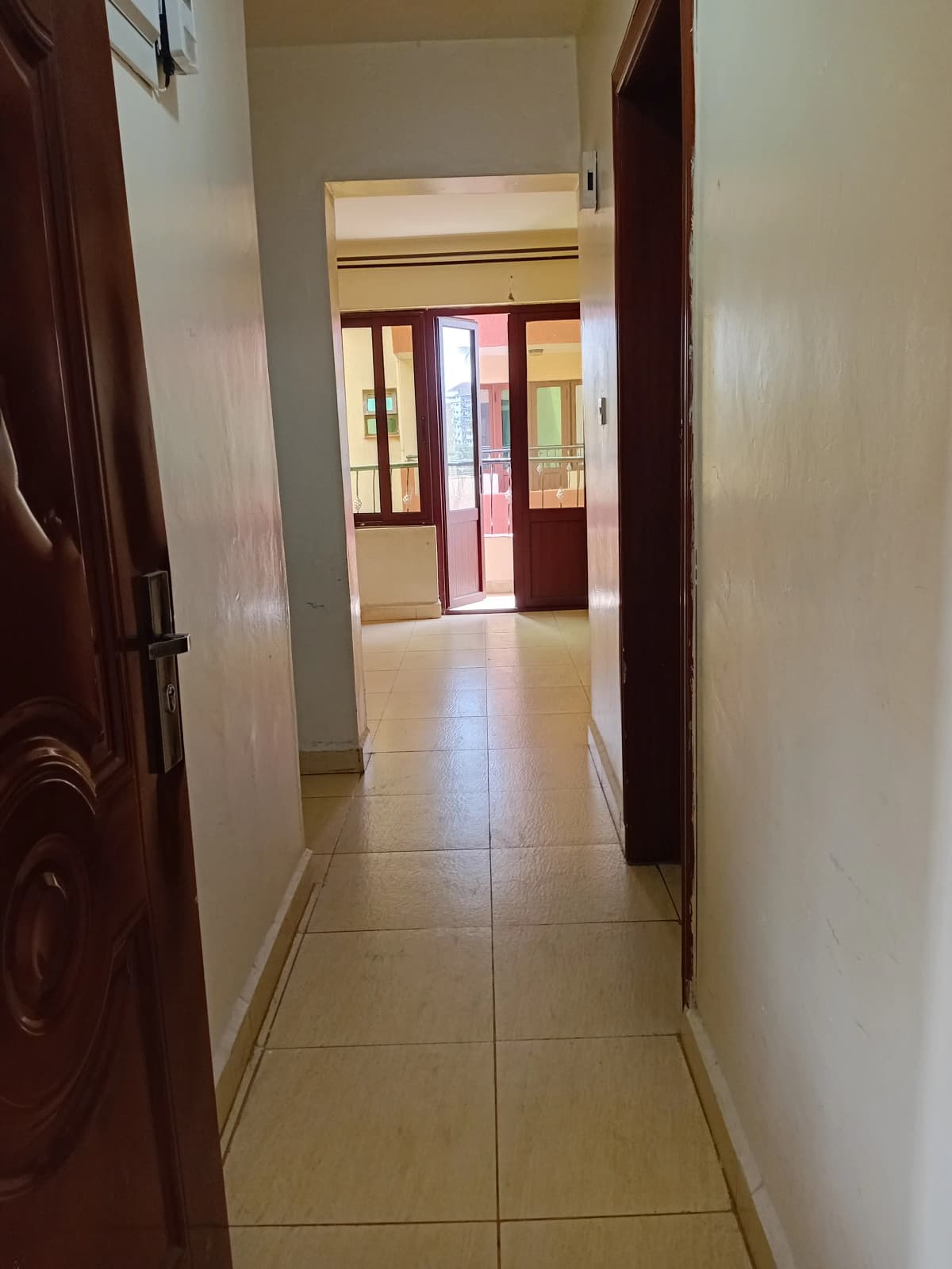 Narrow corridor with tiled flooring and wooden doors