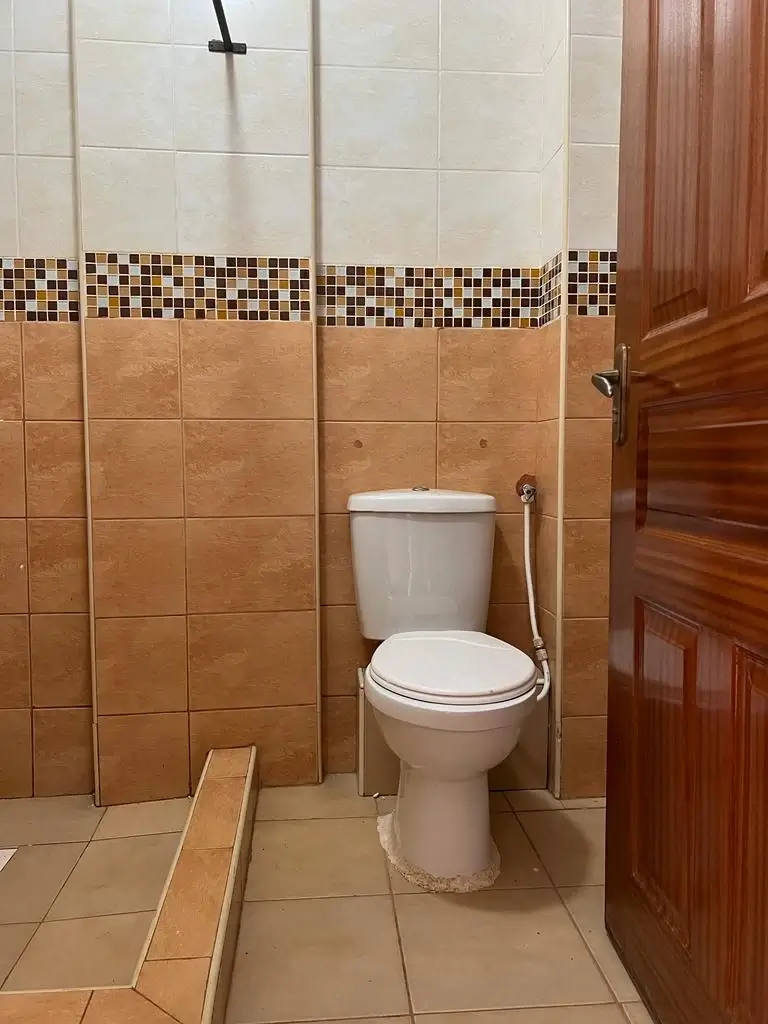 Compact bathroom with ceramic tile walls and toilet fixture