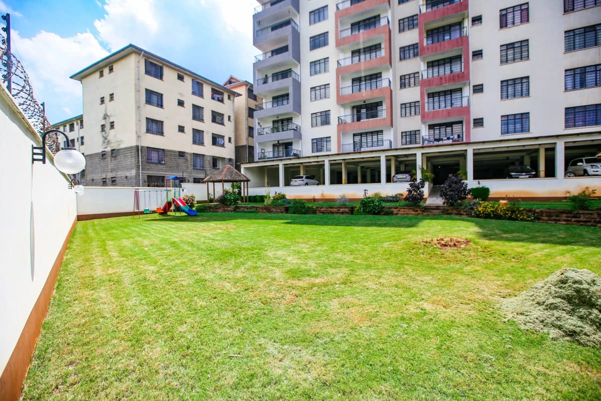 Well-maintained compound lawn with residential buildings backdrop