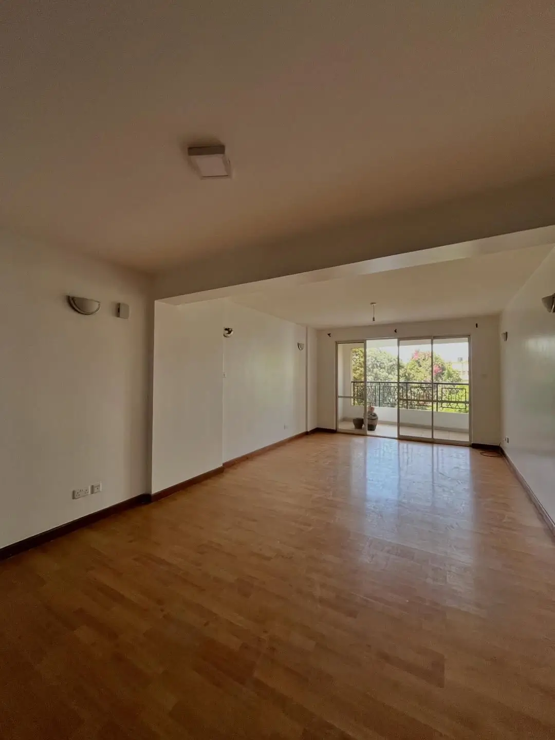 Spacious living room with wooden floors and balcony access