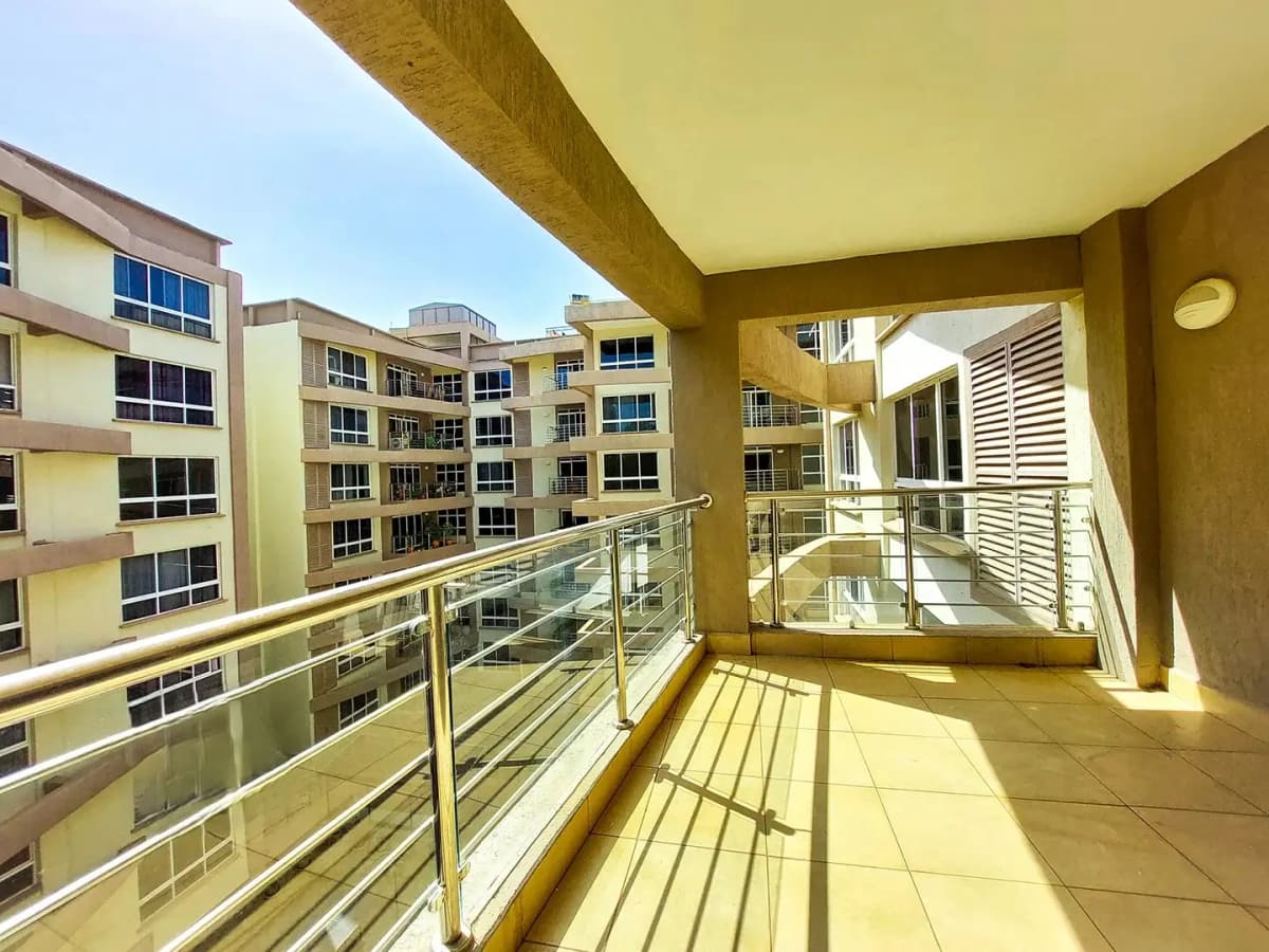 Sunny balcony with glass railings overlooking residential compound
