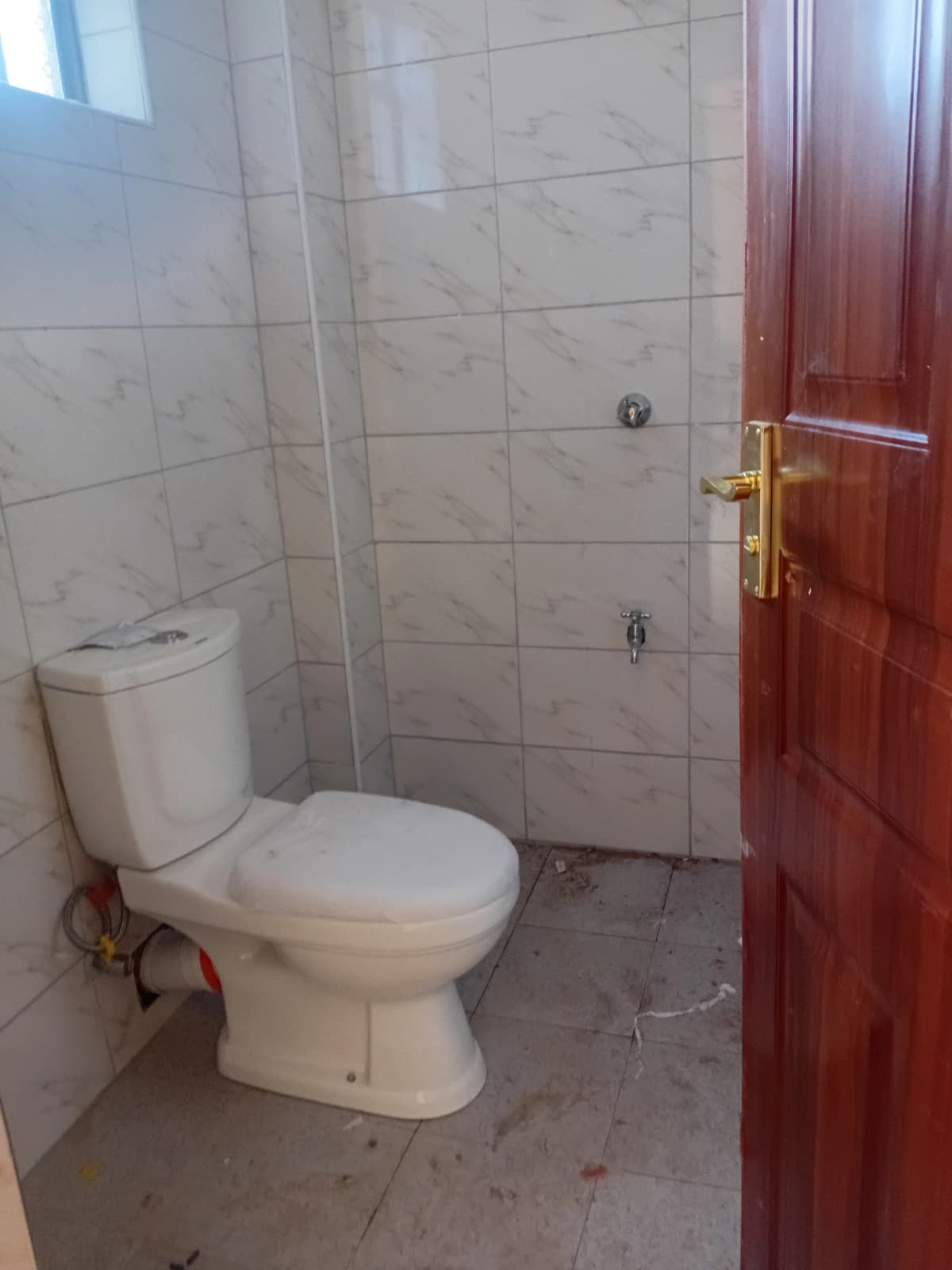 Basic bathroom with toilet, ceramic tiles, red door