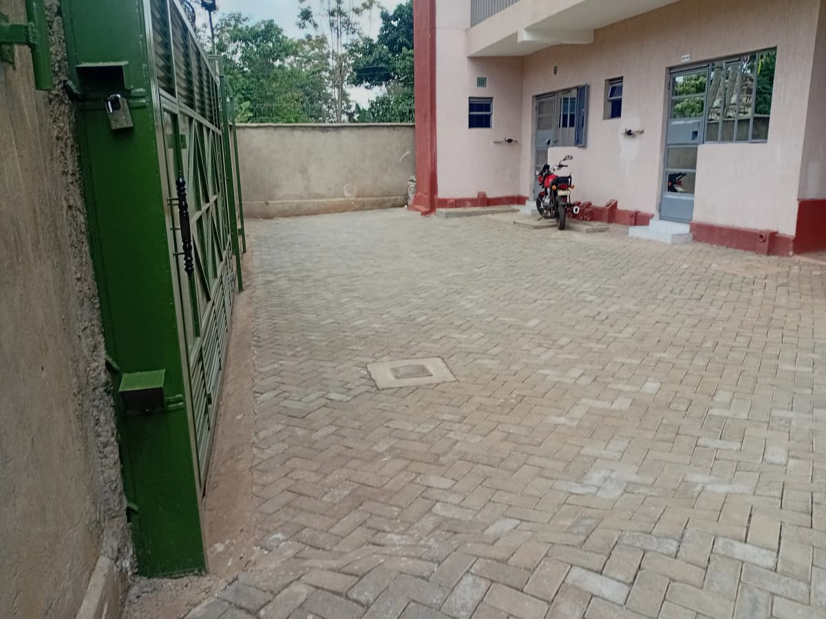 Paved compound entrance with building facade and green gate