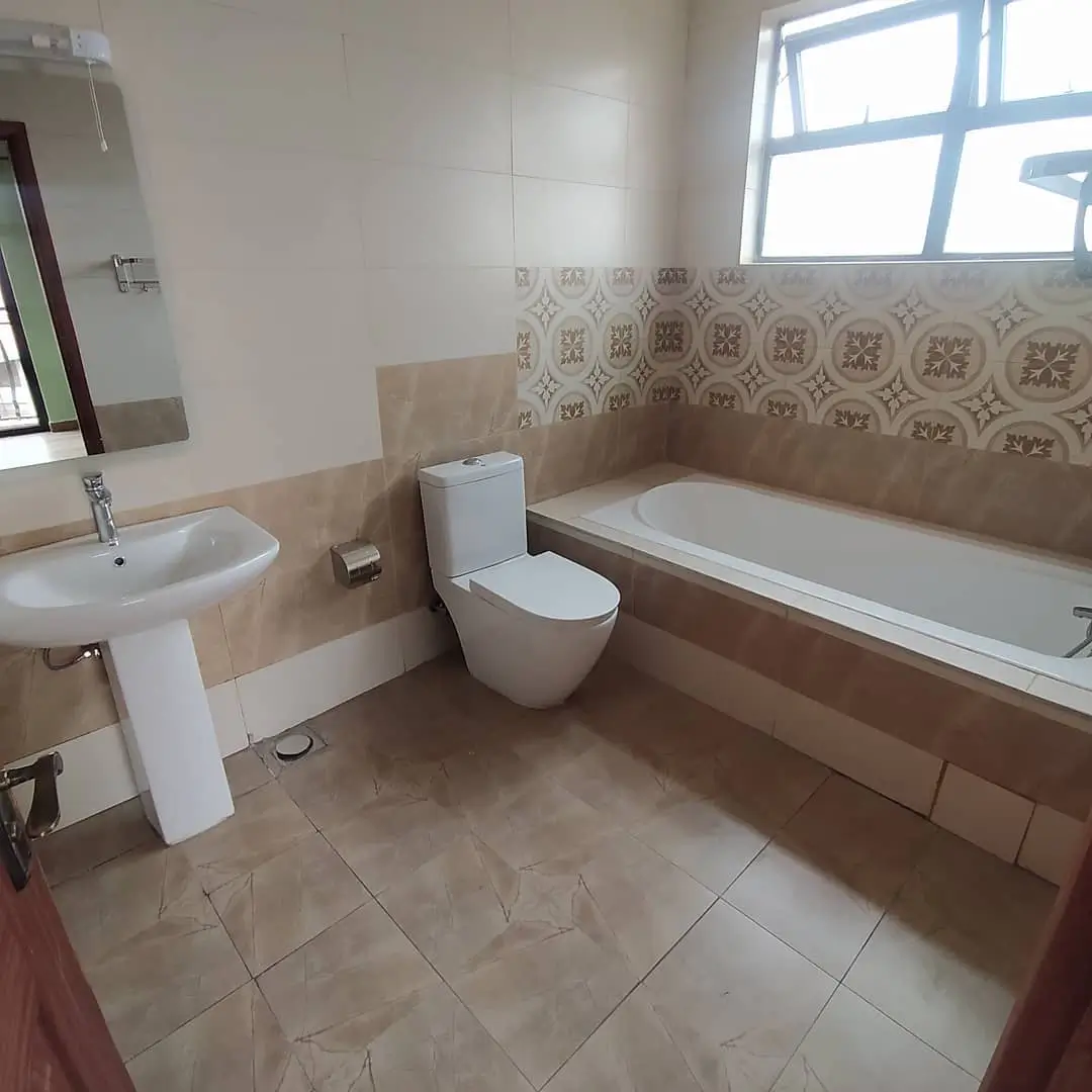 Spacious bathroom with bathtub, toilet, sink, and patterned tiles