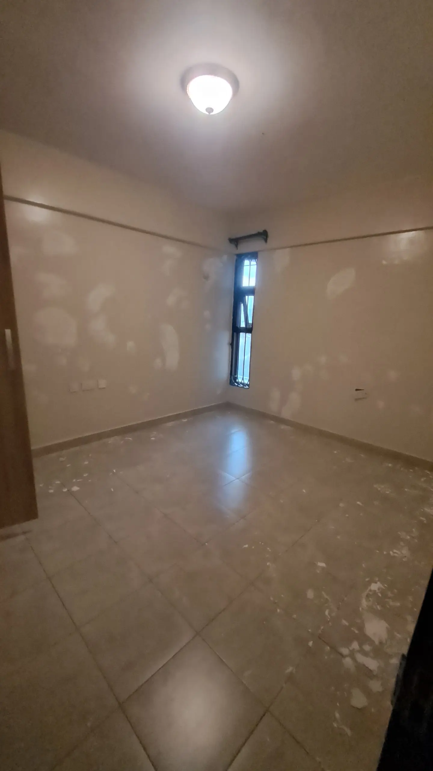 Empty bedroom with polished tile floor and natural light