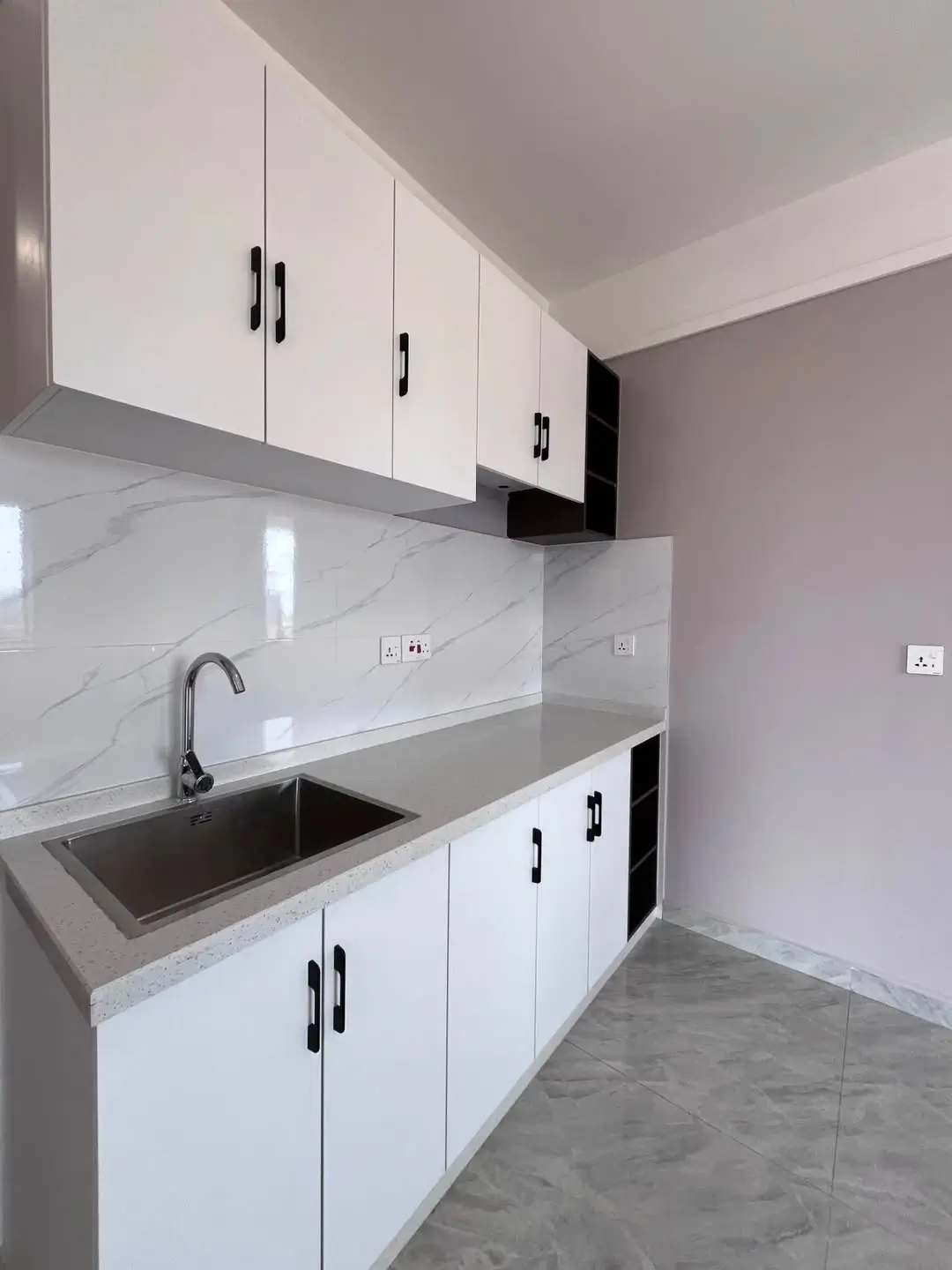 Modern kitchen with white cabinets, marble countertop, sink
