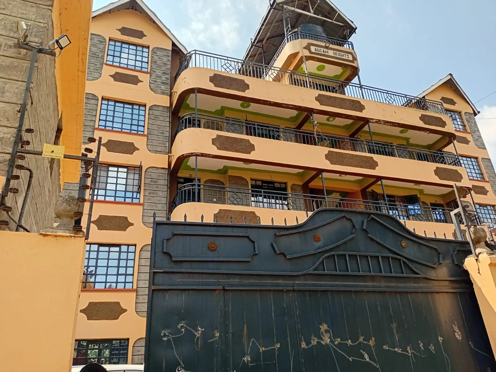Multi-story residential building with yellow facade and metal gate