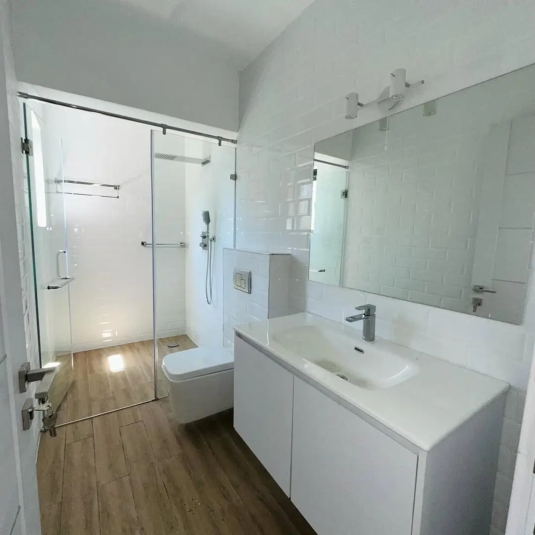 Modern bathroom with walk-in shower, white vanity, mirror