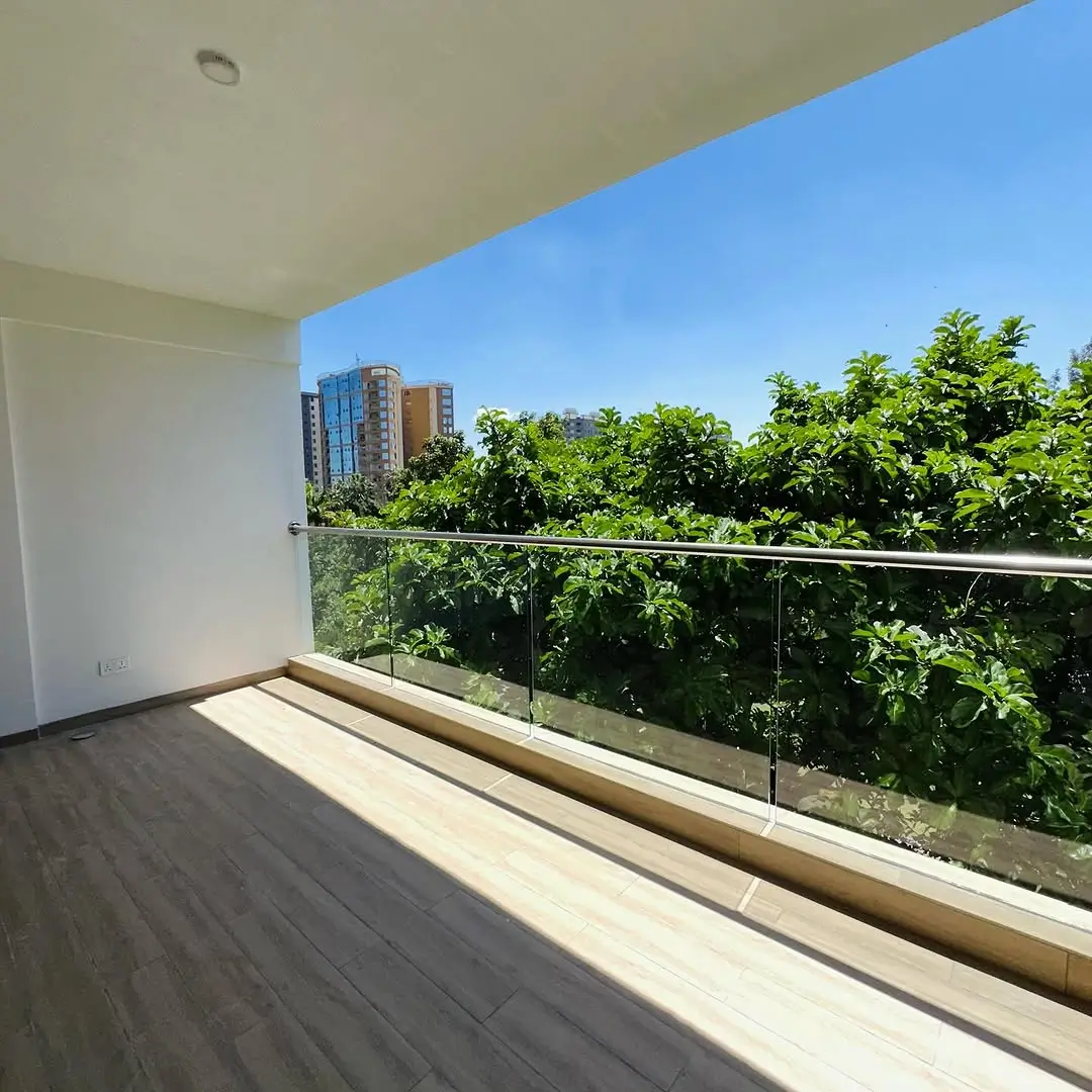 Spacious balcony with city and greenery views, glass railing