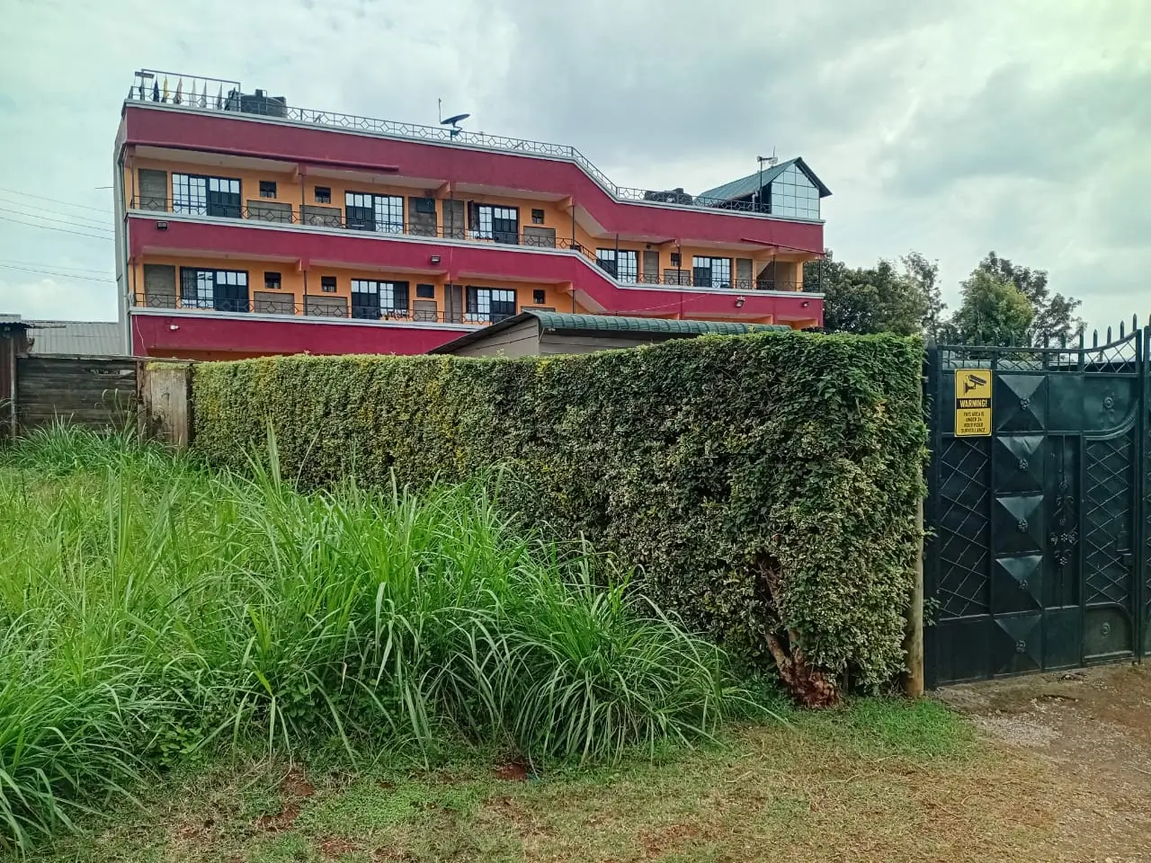 Multi-story residential building with red facade and black gate